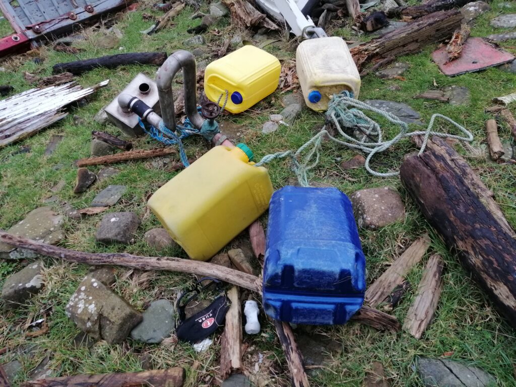 Jerry cans and parts f a wrecked boat on the shore at Fauldbog Bay.