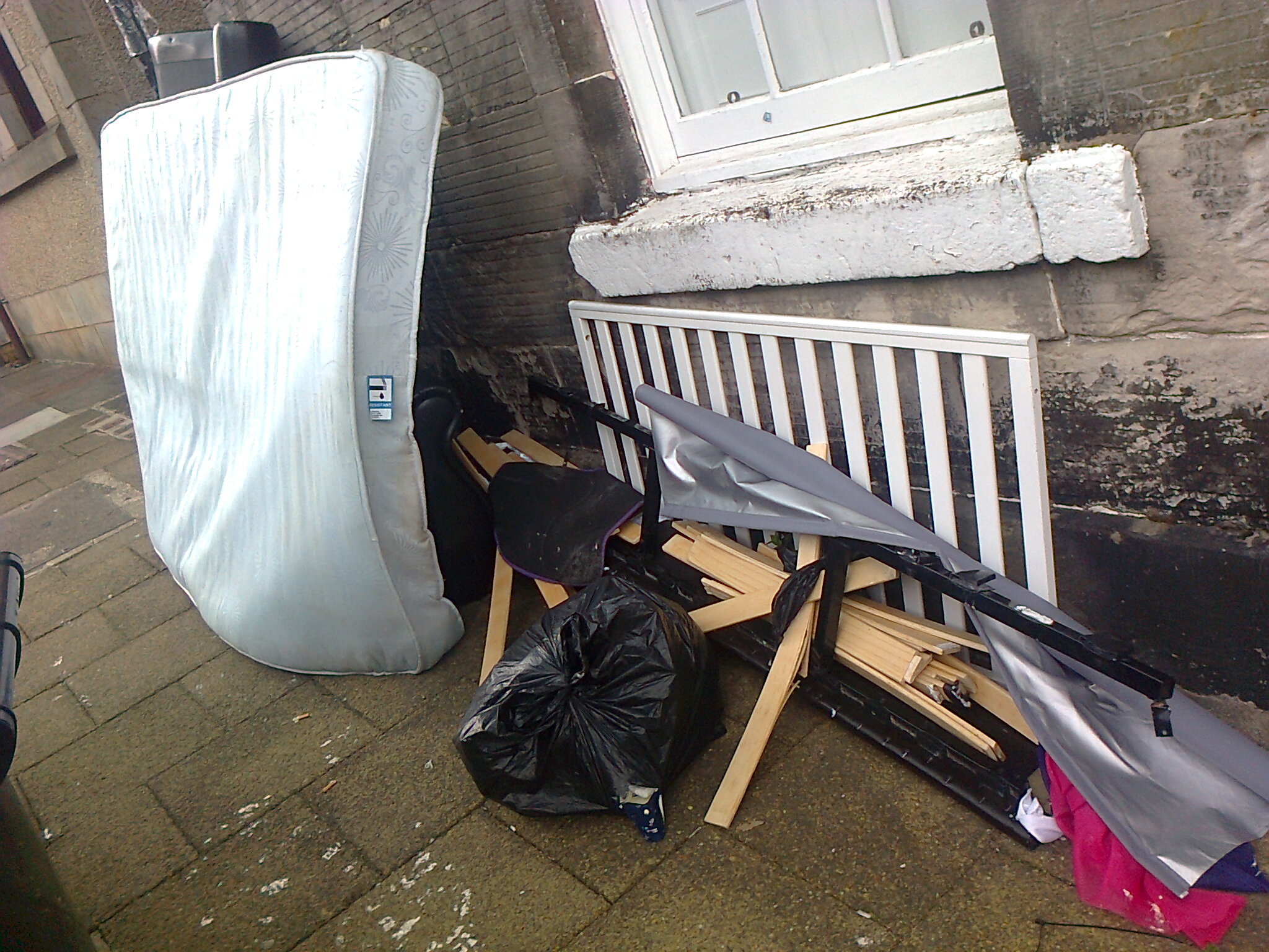A mattress and dismantled bed frame lie on a pavement, propped against the wall of a building in Stirling in 2021.