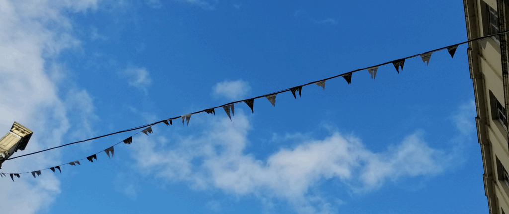 A string of tattered bunting against a blue sky