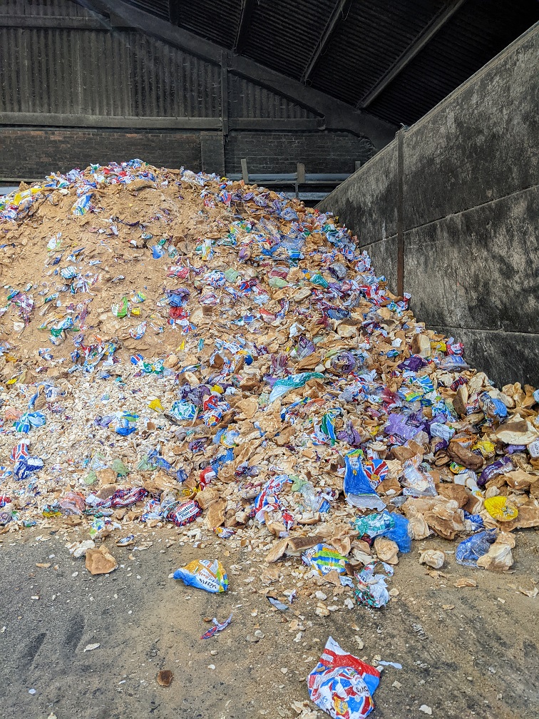 A photograph of a huge pile of scraps of plastic mixed with other unusable waste, taken at a Materials Recovery Facility.